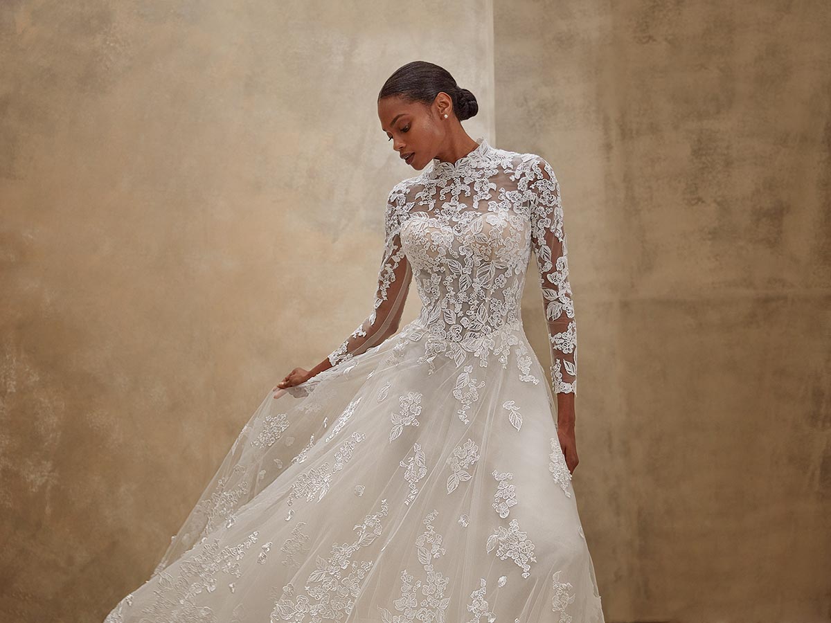 Eine Frau mit elegantem Gesichtsausdruck trägt ein langes weisses Spitzenkleid