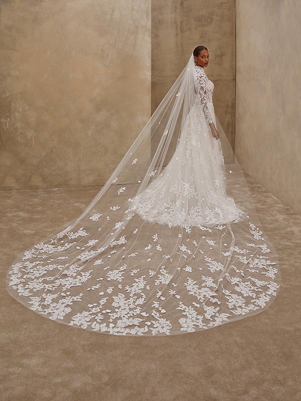 Eine Braut mit ernstem Blick trägt ein elegantes weißes Kleid mit langem Schleier