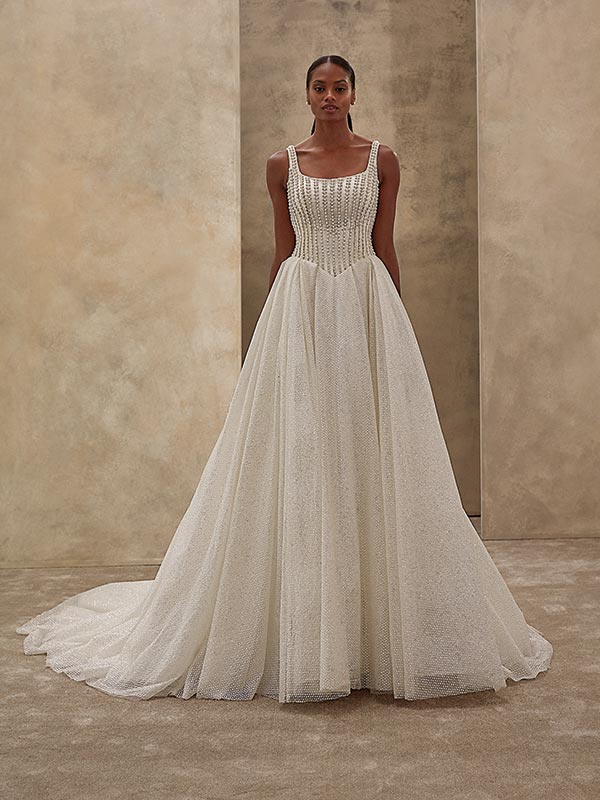 Eine elegante Frau mit neutralem Blick trägt ein funkelndes, weißes Brautkleid