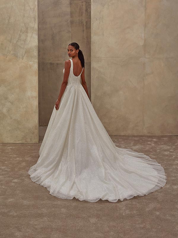 Eine elegant gekleidete Frau im weißen Brautkleid blickt lächelnd über die Schulter