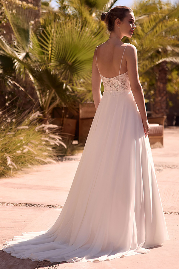 Eine junge Frau mit Hochsteckfrisur steht im Freien in einem eleganten weißen Kleid