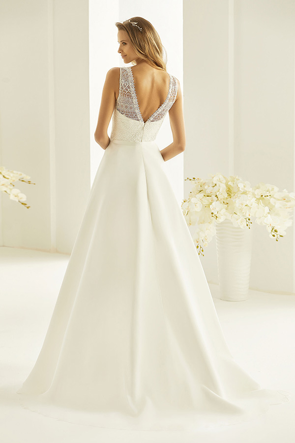 Eine Frau mit offenem Haar trägt ein weißes Brautkleid mit transparentem Rückenteil