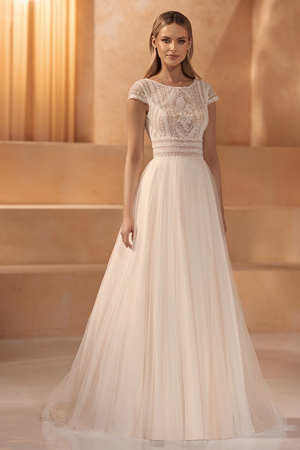 Eine junge Frau mit freundlichem Blick trägt ein elegantes cremefarbenes Brautkleid