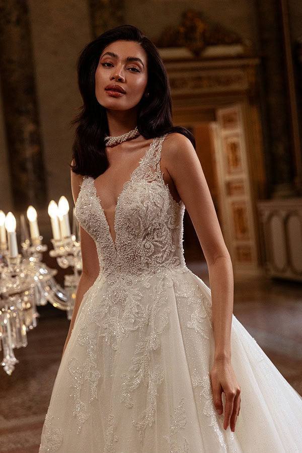 Eine elegante Frau mit langen dunklen Haaren trägt ein aufwendig besticktes Brautkleid