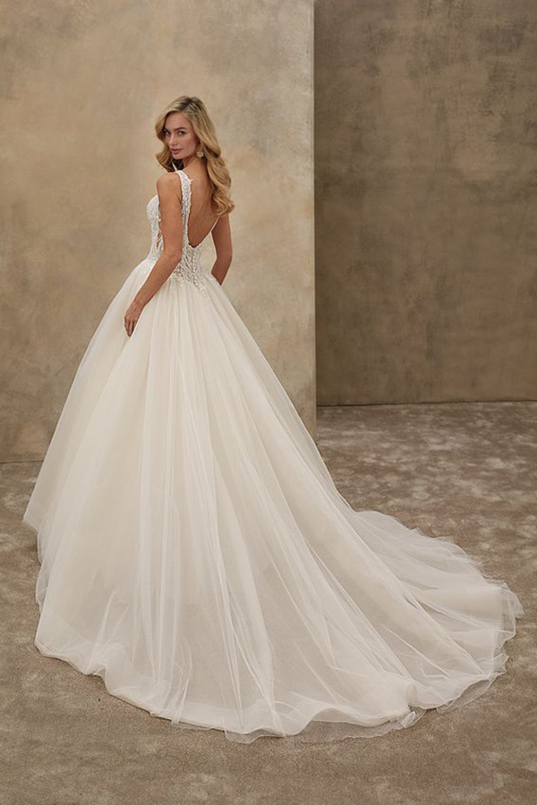 Blonde Frau lächelt leicht in elegantem weißen Brautkleid mit tiefem Rückenausschnitt