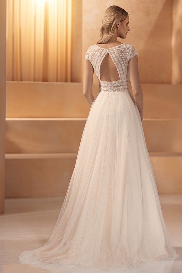 Eine blonde Frau im eleganten cremefarbenen Kleid mit offener Rückenpartie