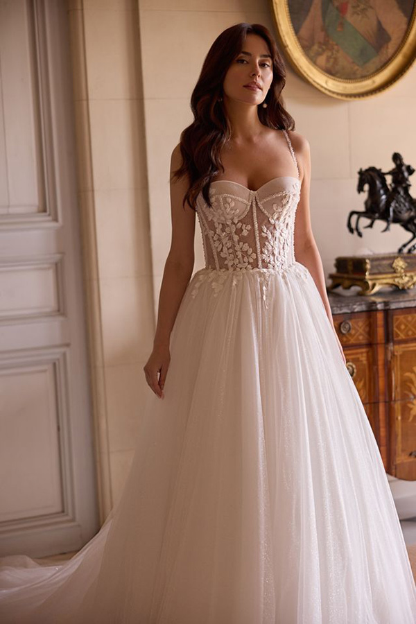 Eine Frau mit langen braunen Haaren trägt ein elegantes cremefarbenes Brautkleid