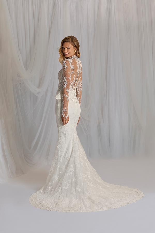 Eine blonde Frau in einem eleganten weißen Spitzenkleid lächelt über die Schulter