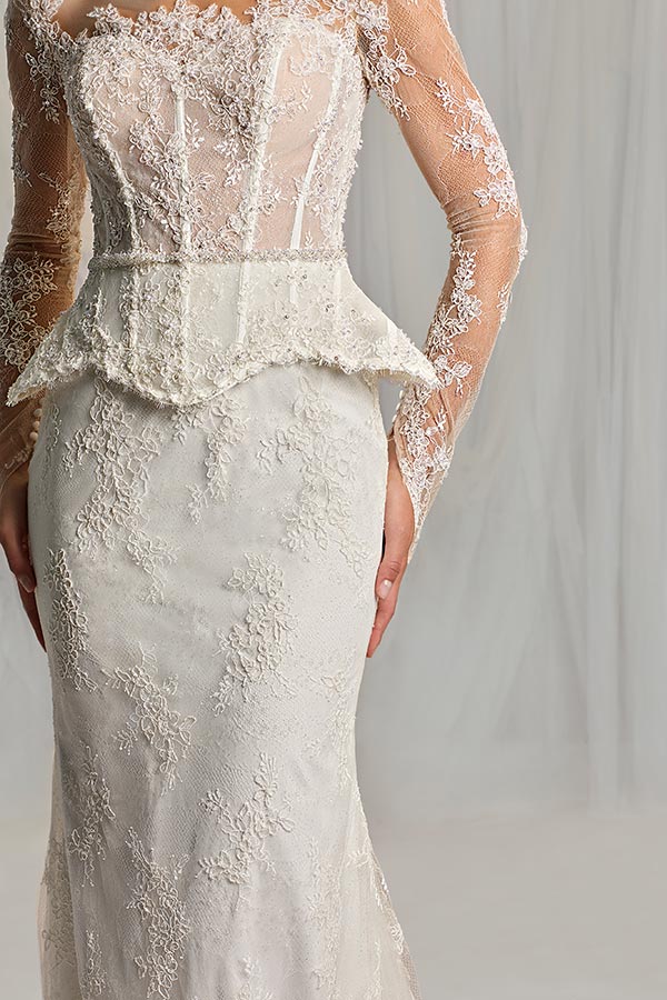 Eine Frau im cremefarbenen Spitzenkleid mit langem Ärmel und dekorativem Mieder