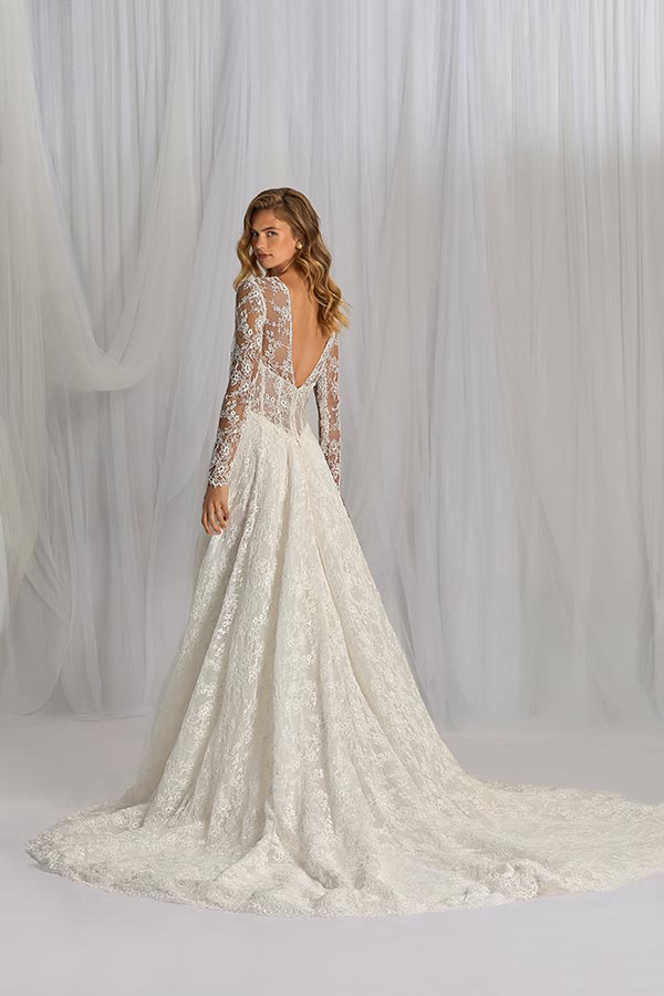 Eine Frau blickt über die Schulter, trägt ein Spitzenkleid in Weiß mit tiefem Rückenausschnitt