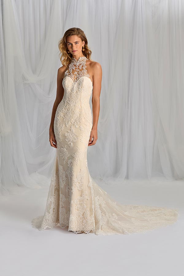 Eine blonde Frau mit entspanntem Gesichtsausdruck trägt ein cremefarbenes Spitzenkleid mit Schleppe