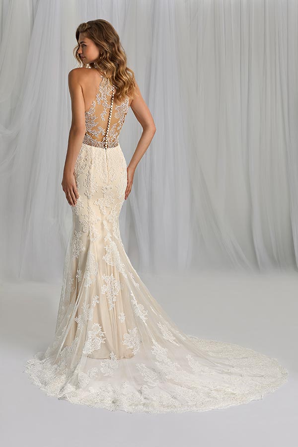 Junge Frau mit welligem Haar trägt ein cremefarbenes Spitzenkleid mit Rückenverzierung