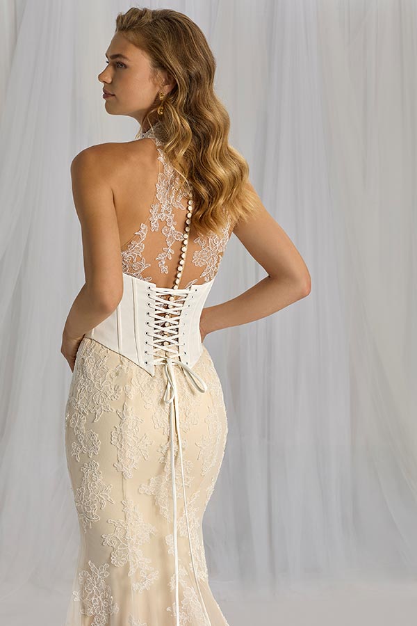 Junge Frau mit sanftem Blick trägt ein elegantes Spitzenkleid in Elfenbein mit Schnürung