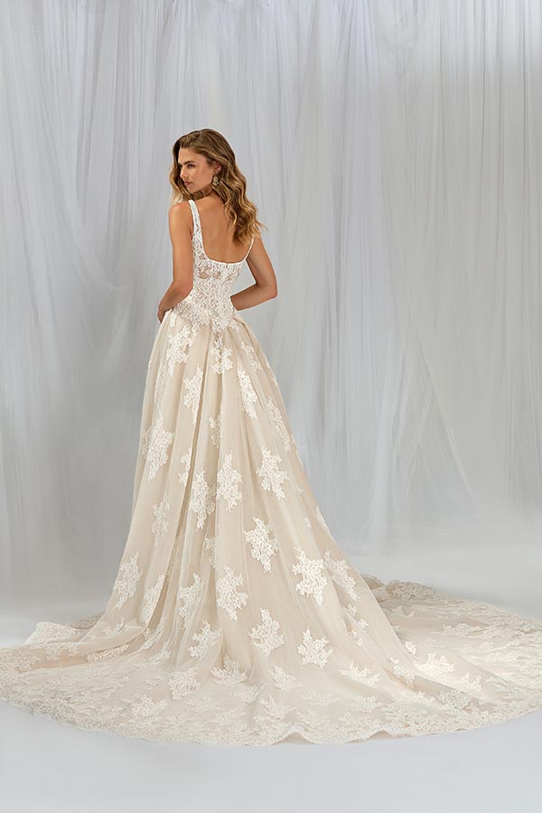 Eine Frau mit langen Wellenhaaren trägt ein elegantes cremefarbenes Spitzenkleid