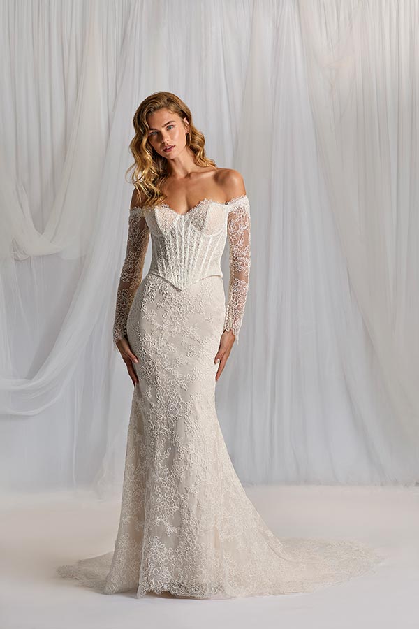 Eine blonde Frau mit lockigem Haar trägt ein elegantes, cremefarbenes Spitzenkleid