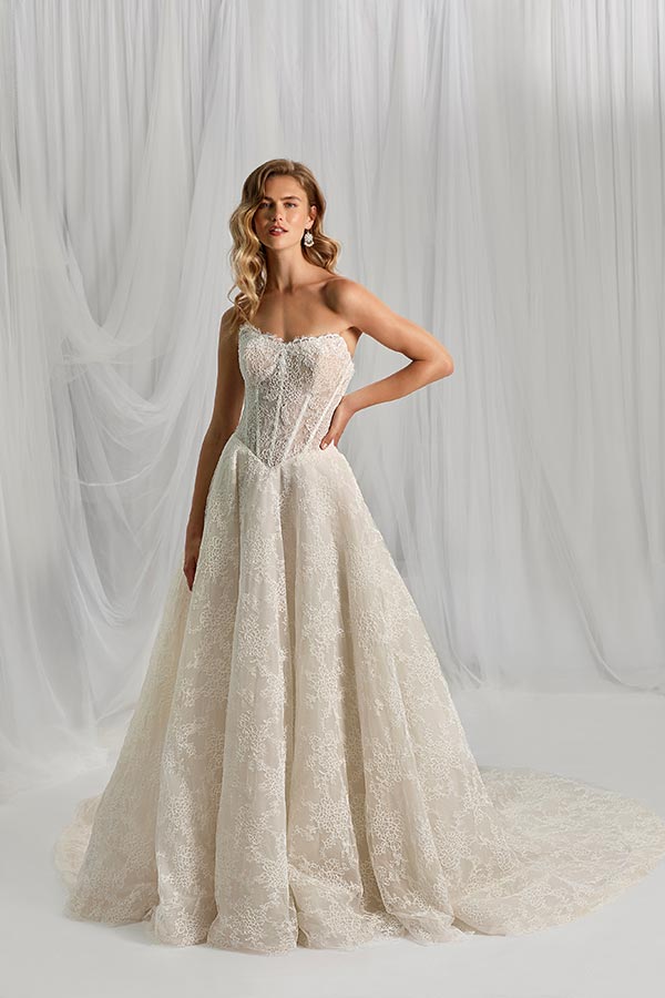 Eine junge Frau mit lockigem blondem Haar trägt ein elegantes cremefarbenes Brautkleid