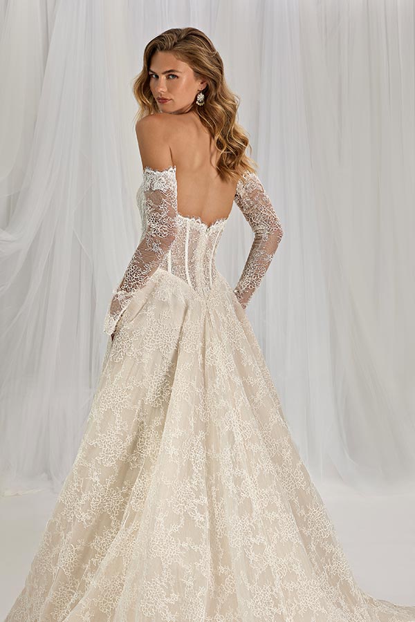 Junge Frau mit offenem Haar trägt ein elegantes cremefarbenes Spitzenkleid und blickt zurück