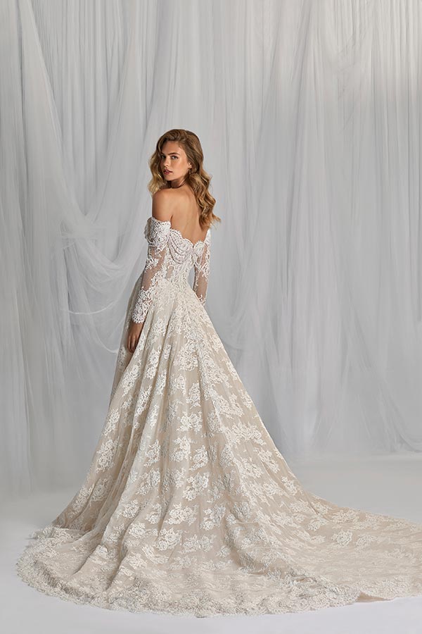 Junge Frau mit sanftem Blick trägt ein cremefarbenes Spitzenkleid mit langer Schleppe