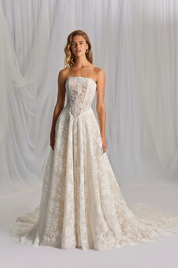 Junge Frau mit langen blonden Haaren im eleganten cremefarbenen Spitzenkleid stehend