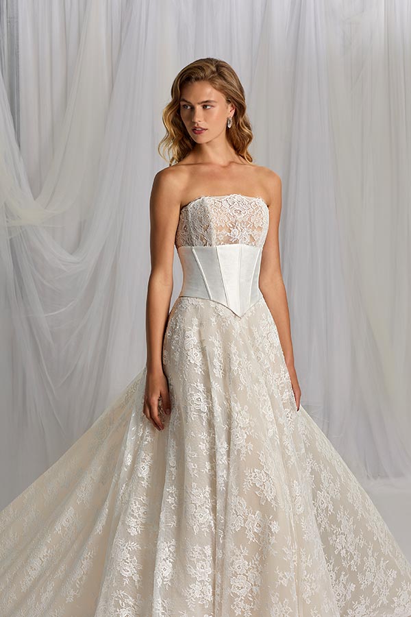 Eine junge Frau mit sanftem Blick trägt ein elegantes Spitzenkleid in Cremeweiß