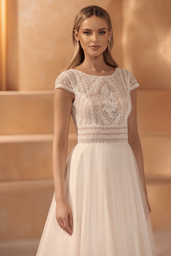 Junge Frau mit langen blonden Haaren und leichtem Lächeln im cremefarbenen Brautkleid