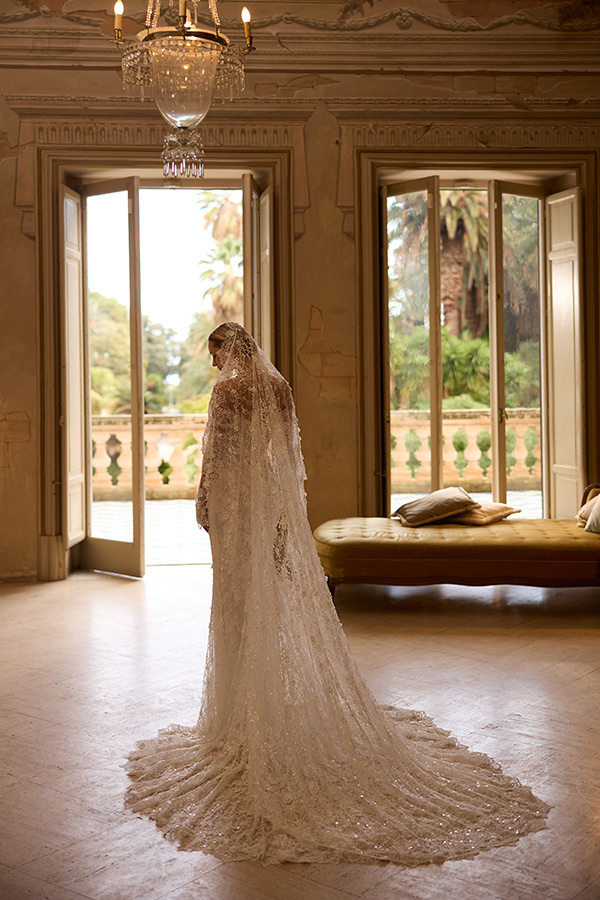 Eine Frau in einem eleganten weißen Brautkleid steht nachdenklich im sonnigen Raum