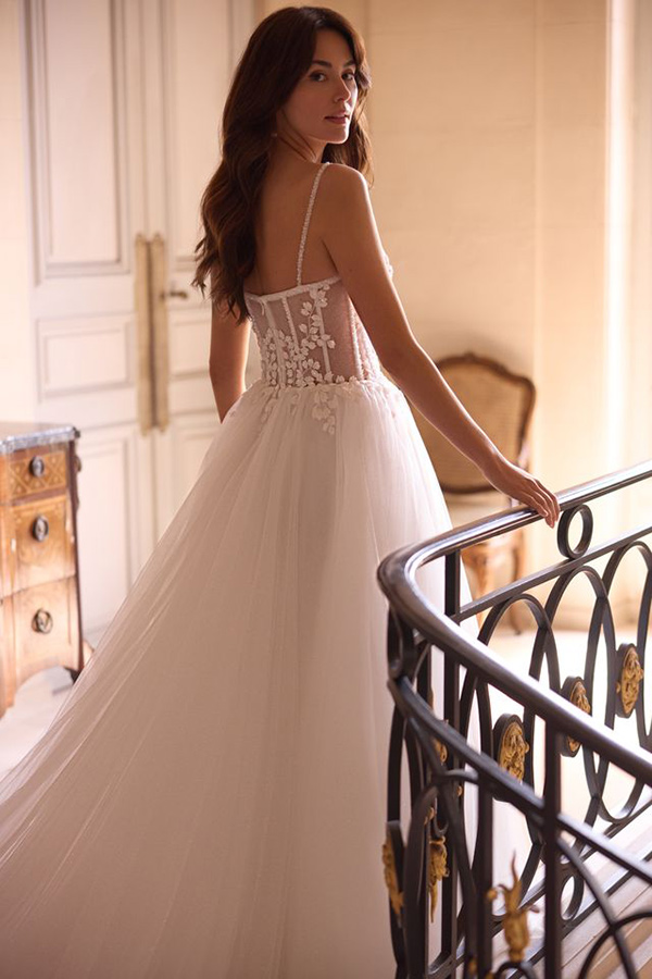 Eine brünette Frau im eleganten weißen Brautkleid blickt nachdenklich über die Schulter