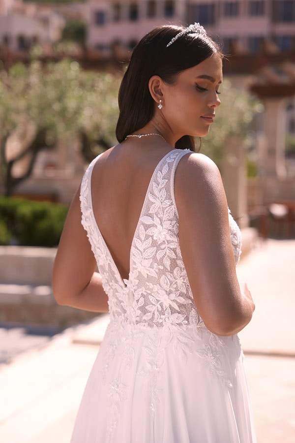 Frau mit ruhigem Gesichtsausdruck trägt weißes Spitzenkleid und Perlenschmuck