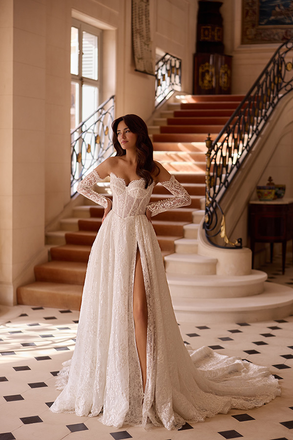 Junge Frau mit lockigem Haar im eleganten weißen Spitzenkleid vor einer Treppe