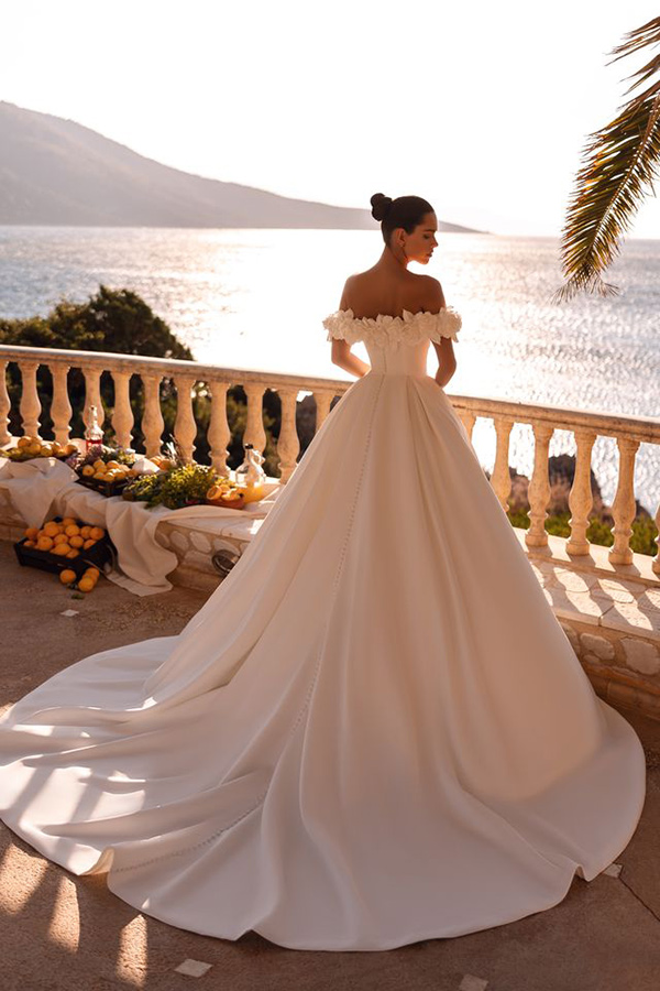 Junge Frau im eleganten weißen Brautkleid blickt lächelnd auf das Meer