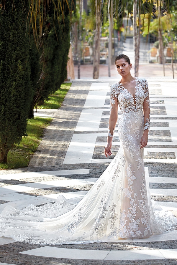 Eine Frau im eleganten cremefarbenen Spitzenkleid steht selbstbewusst im Freien