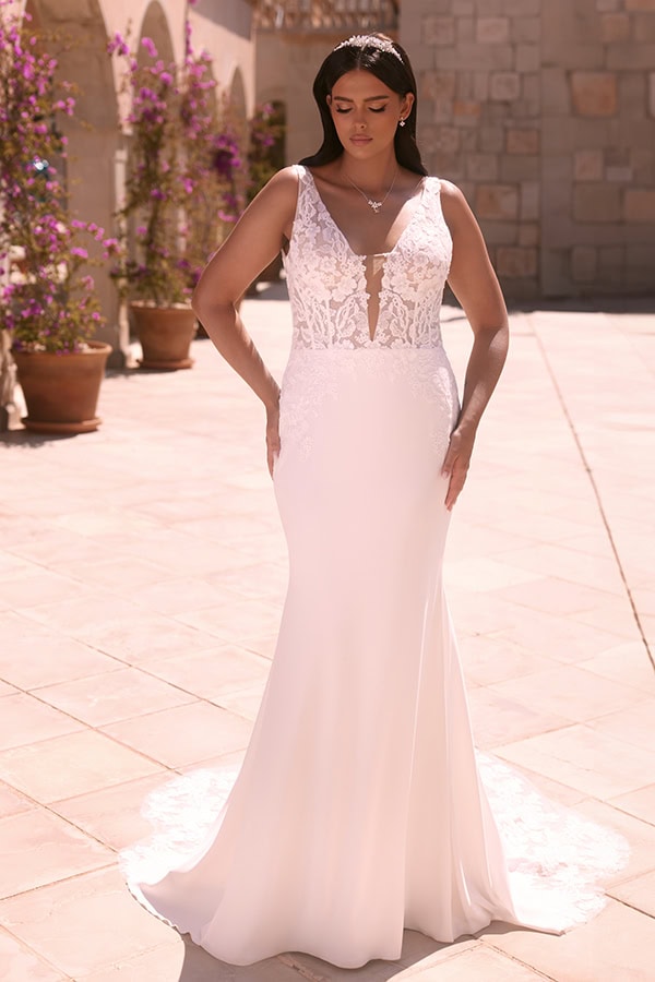 Frau im eleganten cremefarbenen Brautkleid mit Spitzenoberteil steht entspannt draußen