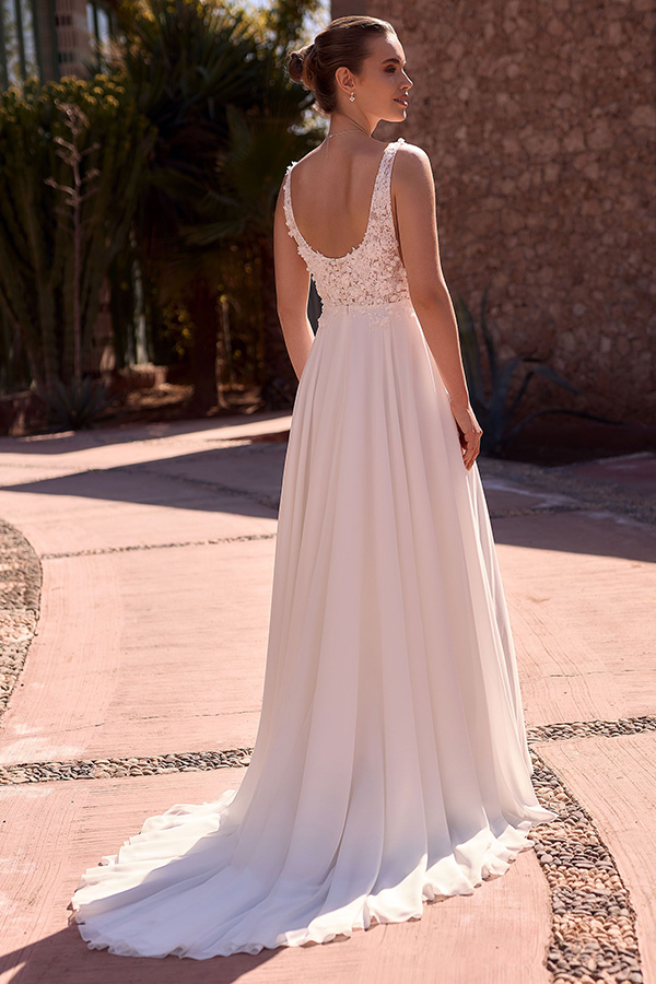 Eine Frau mit elegantem Dutt trägt ein weißes Spitzenkleid und blickt stolz zurück