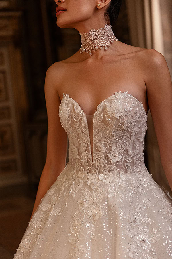 Eine elegante Frau in strahlend weißem, glitzerndem Brautkleid mit Perlenkragen