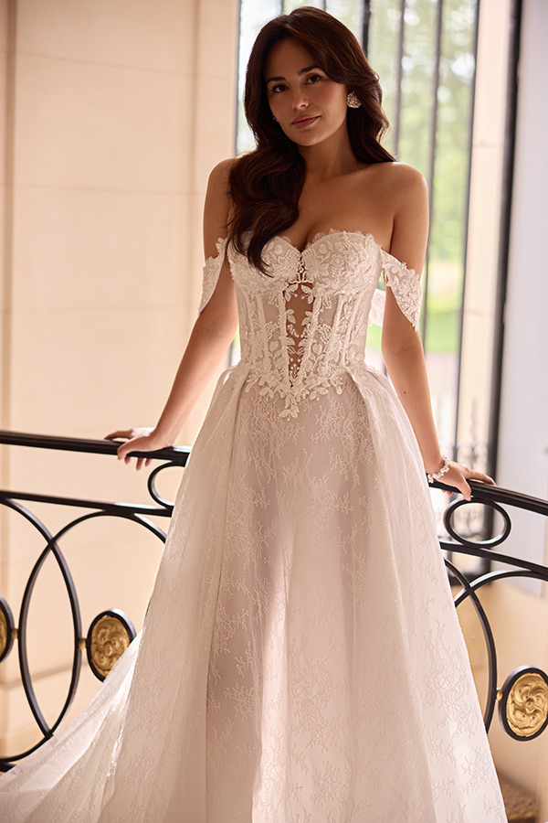 Junge Frau mit langen braunen Haaren lächelt sanft in einem weißen Spitzenkleid