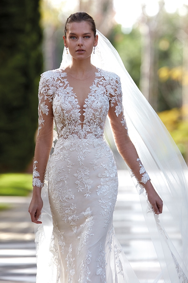 Frau mit ernstem Blick in eleganten weiß bestickten Brautkleid mit langer Schleppe