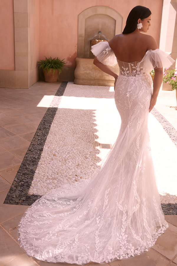 Frau im elfenbeinfarbenen Spitzenkleid mit transparentem Rücken und Tüllärmeln