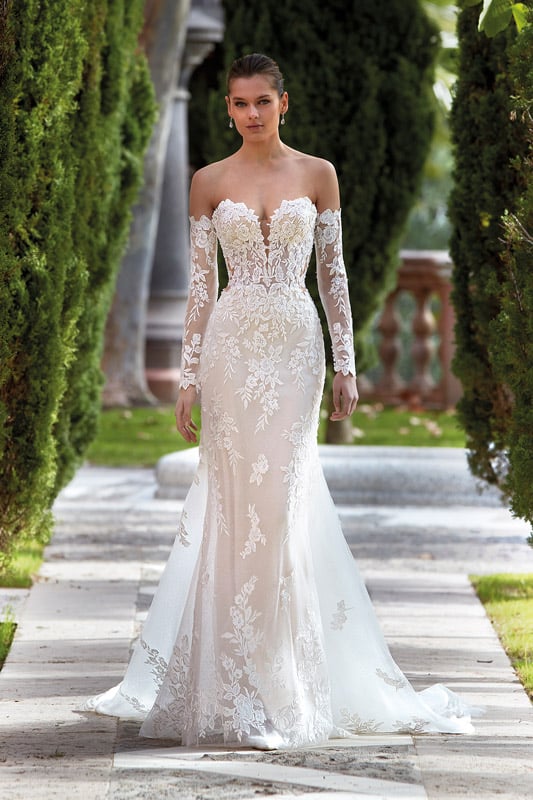 Junge Frau mit ernstem Blick in elegantem cremefarbenem Spitzenkleid mit langen Ärmeln