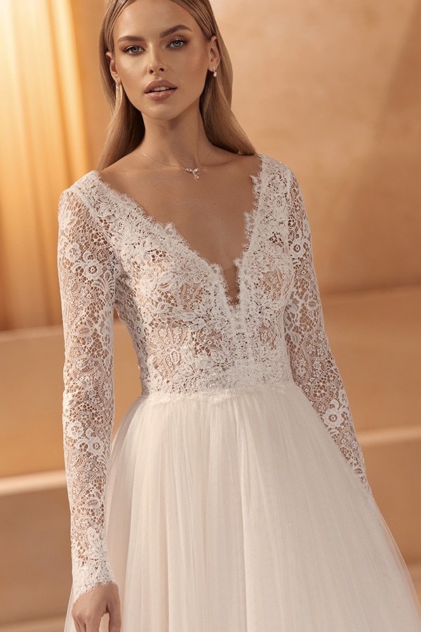 Junge Frau mit ernstem Blick trägt ein elegantes weißes Spitzenkleid mit langen Ärmeln