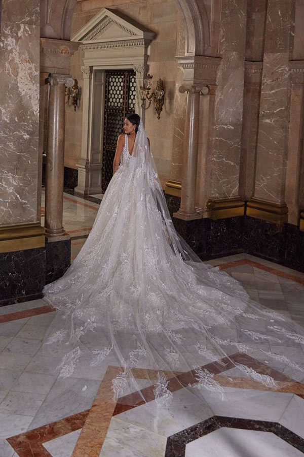 Eine elegant gekleidete Frau im weißen Brautkleid steht vor einer eindrucksvollen Marmorkulisse