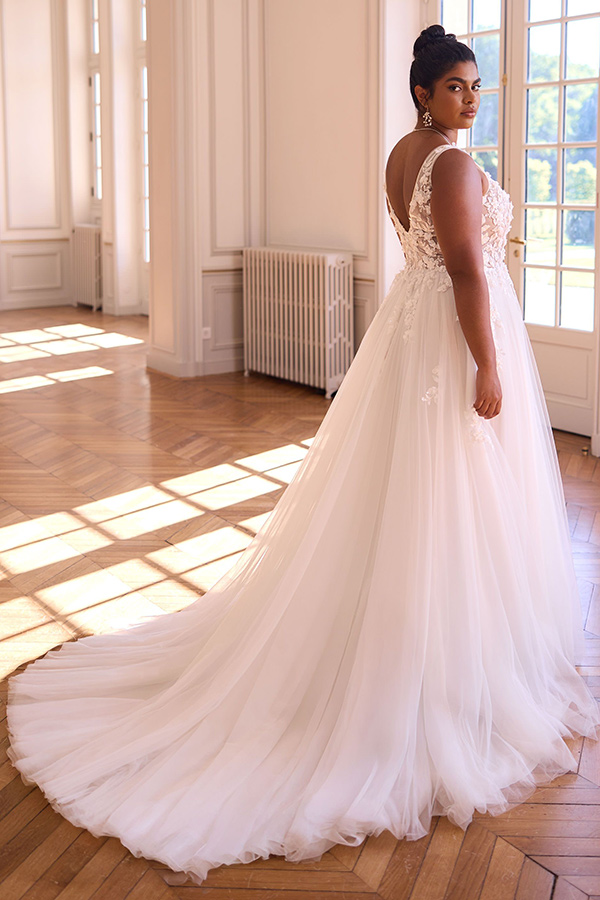 Elegante Frau in cremefarbenem Brautkleid mit Spitze schaut ruhig über die Schulter