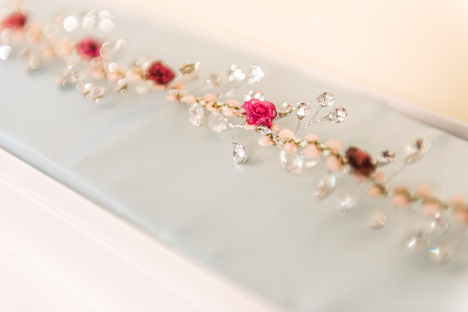 Ein filigranes Armband mit roten Rosen und klaren funkelnden Steinen auf hellem Untergrund