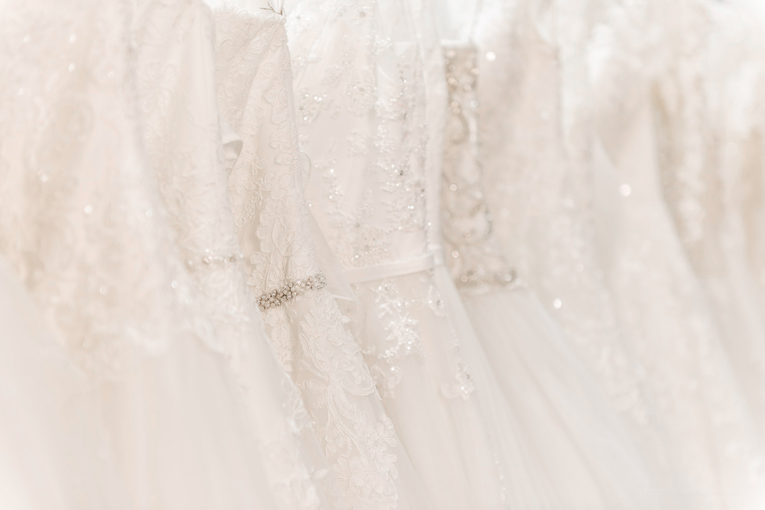 Reihe eleganter weisser Brautkleider mit Spitzenmustern und funkelnden Details