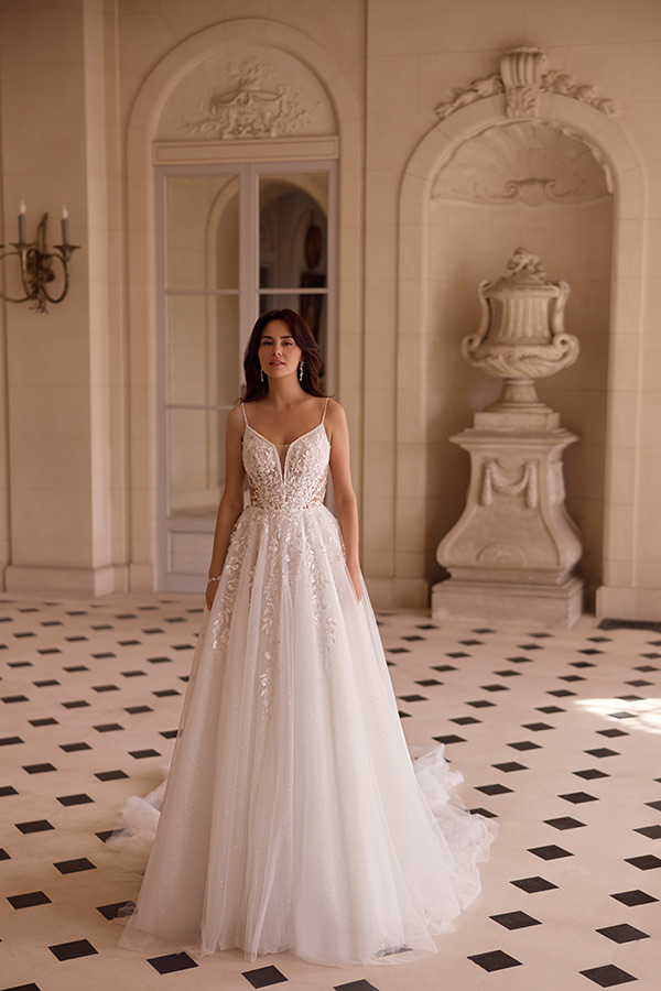 Eine junge Frau mit langen braunen Haaren trägt ein elegantes weißes Brautkleid