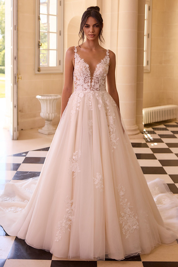 Junge Frau im weißen Spitzenkleid mit schüchternem Lächeln in hellem Raum