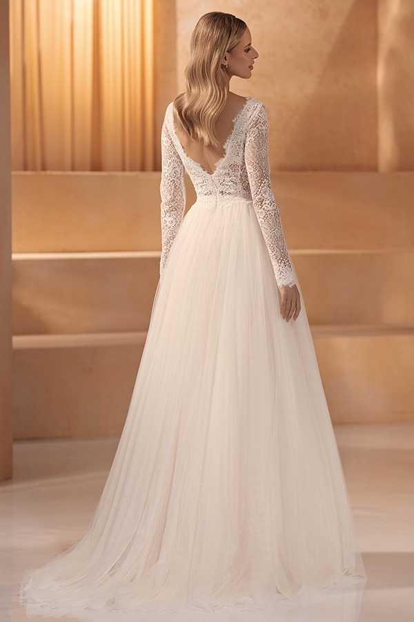 Eine Frau mit blonden Haaren trägt ein elegantes cremeweißes Spitzenkleid mit offenem Rücken