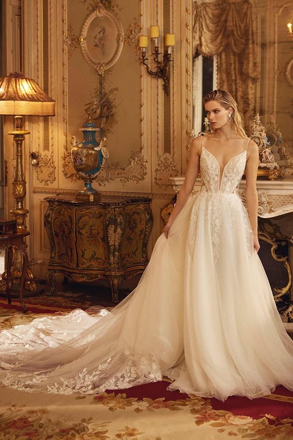 Eine junge Frau im weißen Brautkleid steht nachdenklich in einem prunkvollen Raum