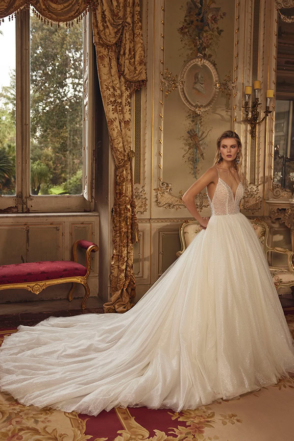 Eine junge Frau mit ernstem Blick trägt ein elegantes, cremeweißes Brautkleid