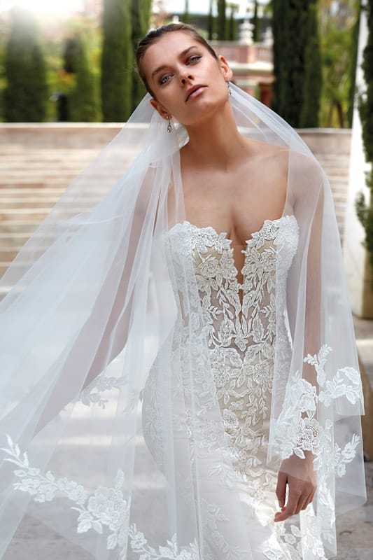 Junge Frau mit ernstem Blick in weißem Spitzenbrautkleid und langem Schleier