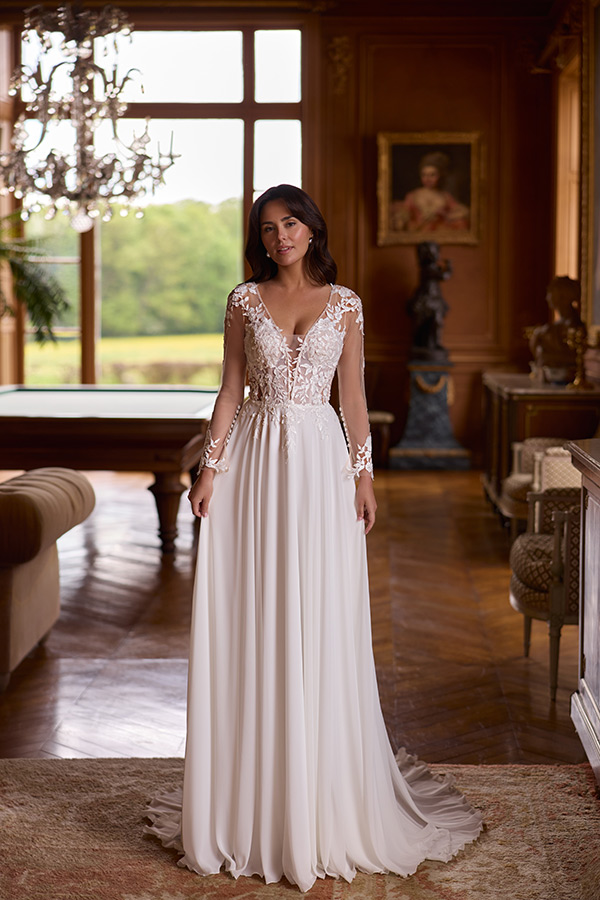 Junge Frau mit braunen Haaren lächelt sanft im eleganten weißen Brautkleid